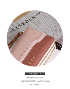 Detail of pink and brown leather wallet featuring pebbled texture and gold zipper