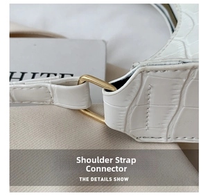 Detail of golden metal buckle and crocodile pattern on white baguette shoulder bag