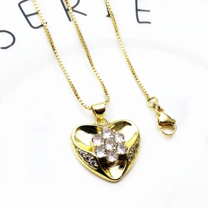 Detailed view of a gold heart pendant with cubic zirconia inlay on a golden box chain