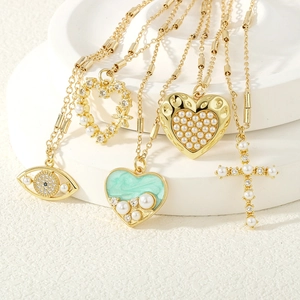 Detail von fünf Goldketten mit Herz-, Kreuz-, Evil Eye-Anhängern und Perlenverzierung