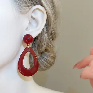 Vintage burgundy resin teardrop dangle earrings with silver needle shown on model