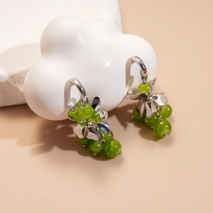 Detail of silver C-shaped grape cluster earrings with textured green glass beads