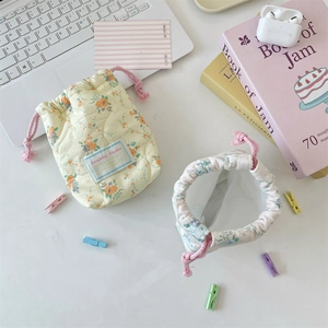 Floral quilted cotton drawstring camera pouch in yellow on a desk with accessories