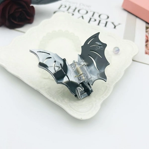 Detail of bat-shaped acetate hair claw clip with dark marble texture on vintage tray