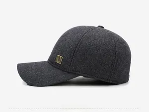 Detail view of dark gray wool baseball cap featuring a side vintage gold metal plaque