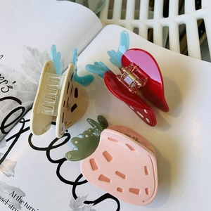 Detailed view of three cute strawberry-shaped hair claws in pastel pink and vibrant red