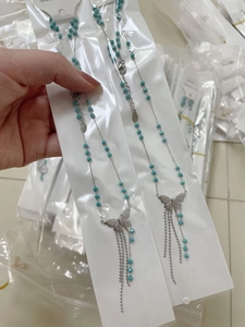 Detail of beaded tassel butterfly necklace in silver stainless steel with blue beads