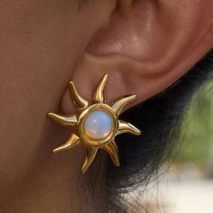Elegant gold sun-shaped earrings with round moonstone inlay worn by a female model