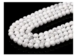Macro detail of natural white howlite beads with grey veins on a black background