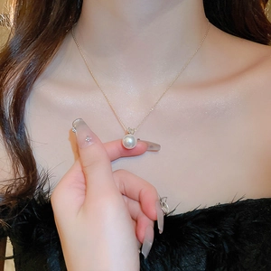 Elegant gold pearl necklace with zircon accents worn by a model on a black top