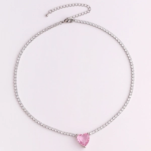 Detail of silver tennis chain necklace featuring a central pink heart-shaped crystal