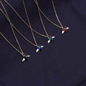 Detail of angel wing heart necklaces in black, blue, green, and red gold-plated finish