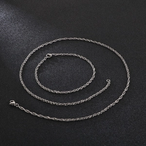 Detail shot of silver rope chain necklace set with metallic texture on dark background