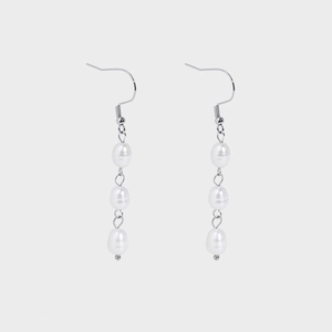 Detail of silver drop earrings featuring a cascading trio of baroque freshwater pearls