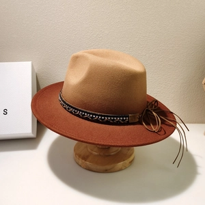 Detail of two-tone fedora hat with woven rhinestone band and decorative tassels