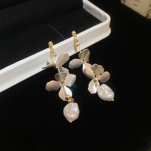 Detail of matte gold floral earrings featuring baroque pearls on black velvet display