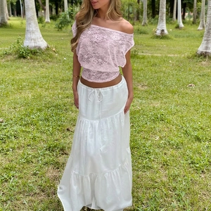 Detalle del top de encaje rosa con hombros descubiertos y falda blanca con volantes