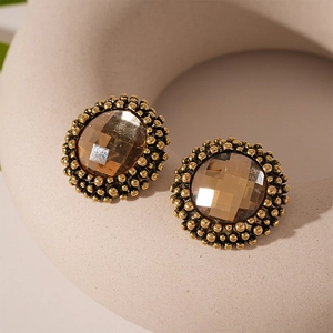 Macro detail of vintage round stud earrings with amber stone and beaded gold trim