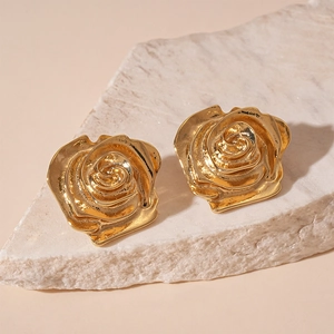 Gros plan de boucles d'oreilles rose dorée avec texture vintage sur pierre