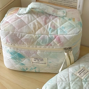 Macro view of quilted watercolor makeup bag with metal zipper and soft fabric texture