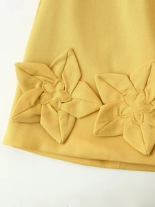 Gros plan sur la broderie florale 3D et le tissu en sergé d'une robe jaune gingembre
