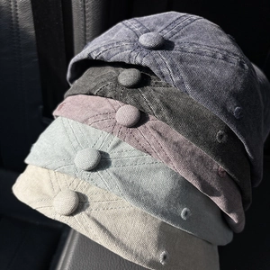 Five assorted vintage washed cotton baseball caps stacked on a dark leather surface