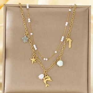 Vue détaillée du collier doré à plusieurs rangs avec breloques sur fond de soie