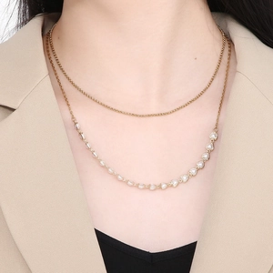 Close-up of double-layered gold necklace with heart and pearl pendant on model