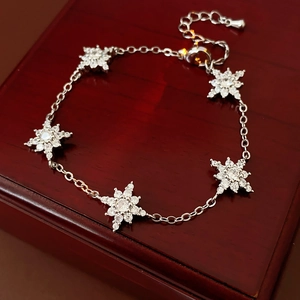 Détail d'un bracelet flocon de neige en argent avec zircons sur un coffret en bois rouge