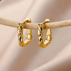 Elegant 18K gold-plated hammered texture oval hoop earrings on rustic branch