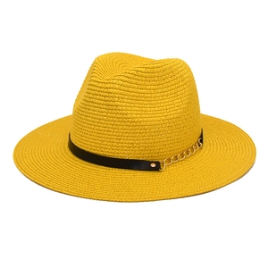 Detail of yellow straw fedora with black leather band and gold chain decoration