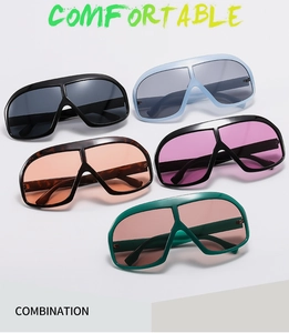 Flat lay of oversized shield sunglasses in five trendy colors on a grey background