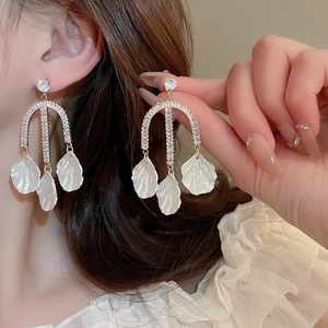 Detailed view of elegant gold-plated floral earrings with white petals and tassels