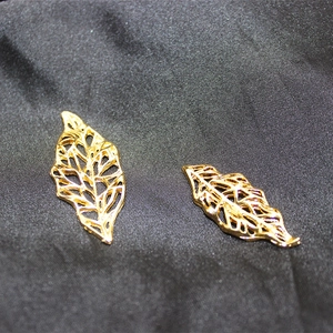Macro shot of two golden hollow leaf charms for DIY bridal hair jewelry and accessories