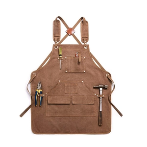 Flat lay of brown canvas work apron with leather straps and multiple tool pockets