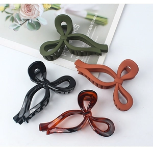 Detail view showing four matte and glossy hollow bow hair claws in various colors