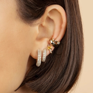 Close-up of stacked 18K gold hoop earrings with zircon micro-pave and a yellow gemstone