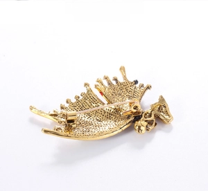 Detailed back view of vintage gold-tone brooch showing sturdy metal pin and grainy texture