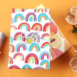 Geschenkpapierrolle mit Regenbogenmuster, dekorativer Kordel und bunten Siegelaufklebern