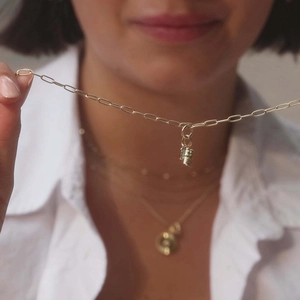Detailed view of two gold birthstone cube pendants on a stainless steel chain worn by a model