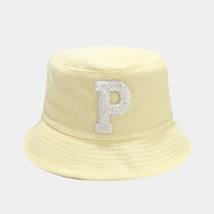 Détail du tissu éponge du bob jaune avec un écusson lettre P blanc doux et texturé