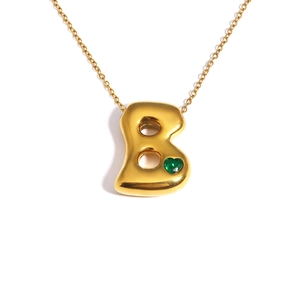 Detail of 18k gold plated bubble letter B necklace with a green heart gemstone inlay