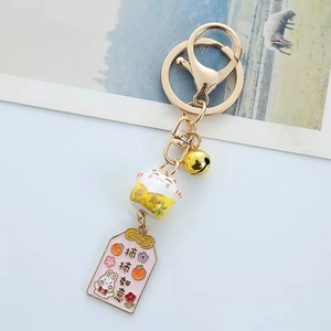 Detailed close-up of a Japanese ceramic fortune cat keychain with golden bell and charms
