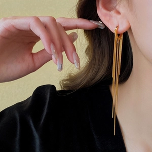 Gros plan d'élégantes boucles d'oreilles pendantes à longs pompons dorés sur un mannequin