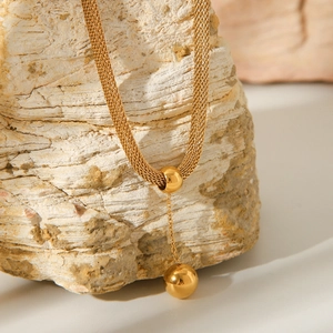 Detail view of 18K gold plated stainless steel flat woven chain and ball pendant necklace