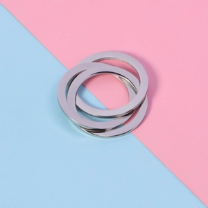 Macro shot of silver interlocking triple rolling rings over pink and blue background