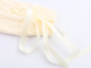Detail of cream white cable knit texture with elegant satin ribbon bow decoration