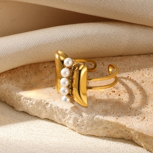 Macro detail of adjustable gold pearl ring showing four pearls on a textured stone surface
