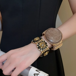 Close-up of vintage gold floral enamel bracelet and rutile quartz wrap bangle