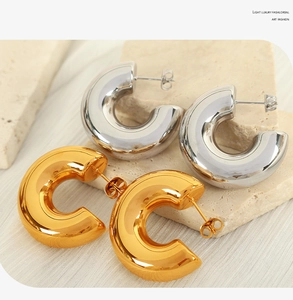Minimalist C-shaped hoop earrings in gold and silver finish on textured stone